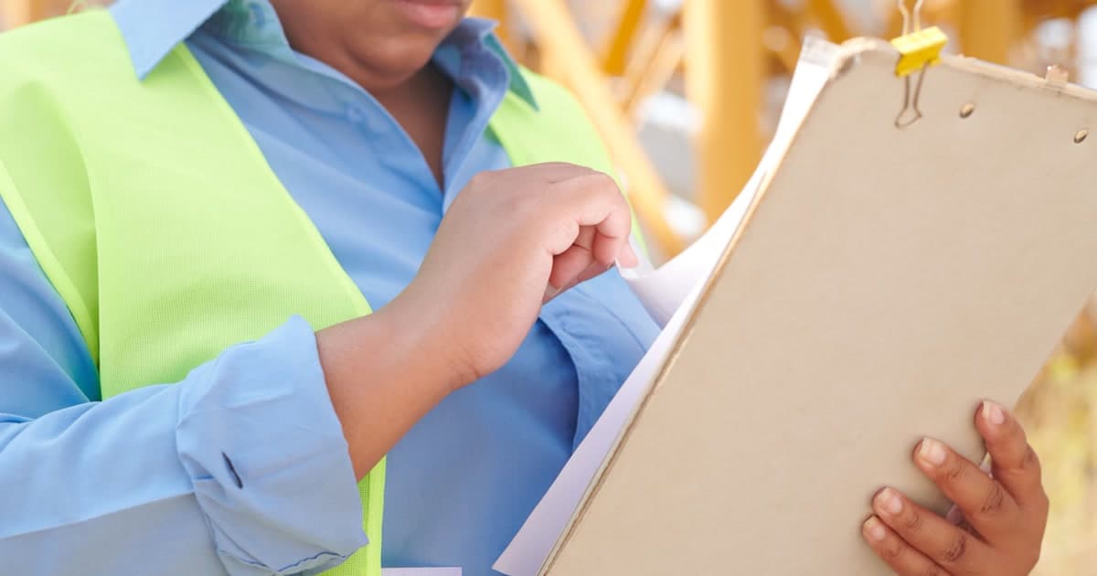 A contractor in a hard hat reviewing risk assessment documents on a construction site.