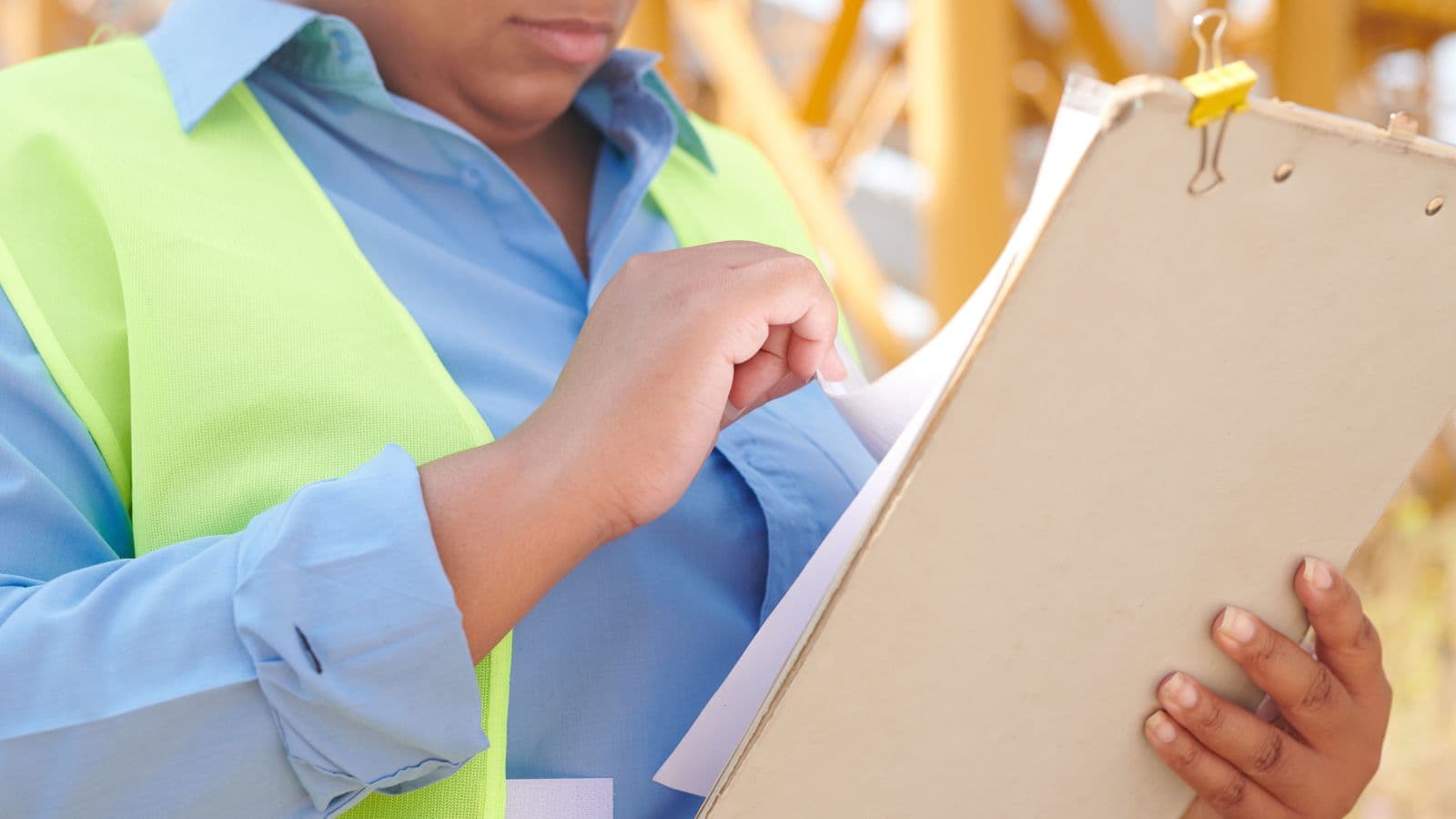 A construction worker in high-vis reviewing building documents on site before starting work