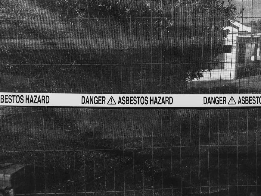 A construction worker examining suspected asbestos material on site