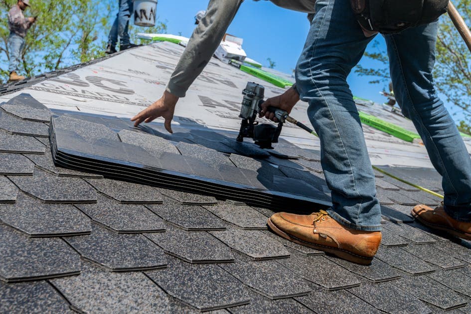 a roofer in full PPE including harness and safety line working near a fragile fibre cement roof edge