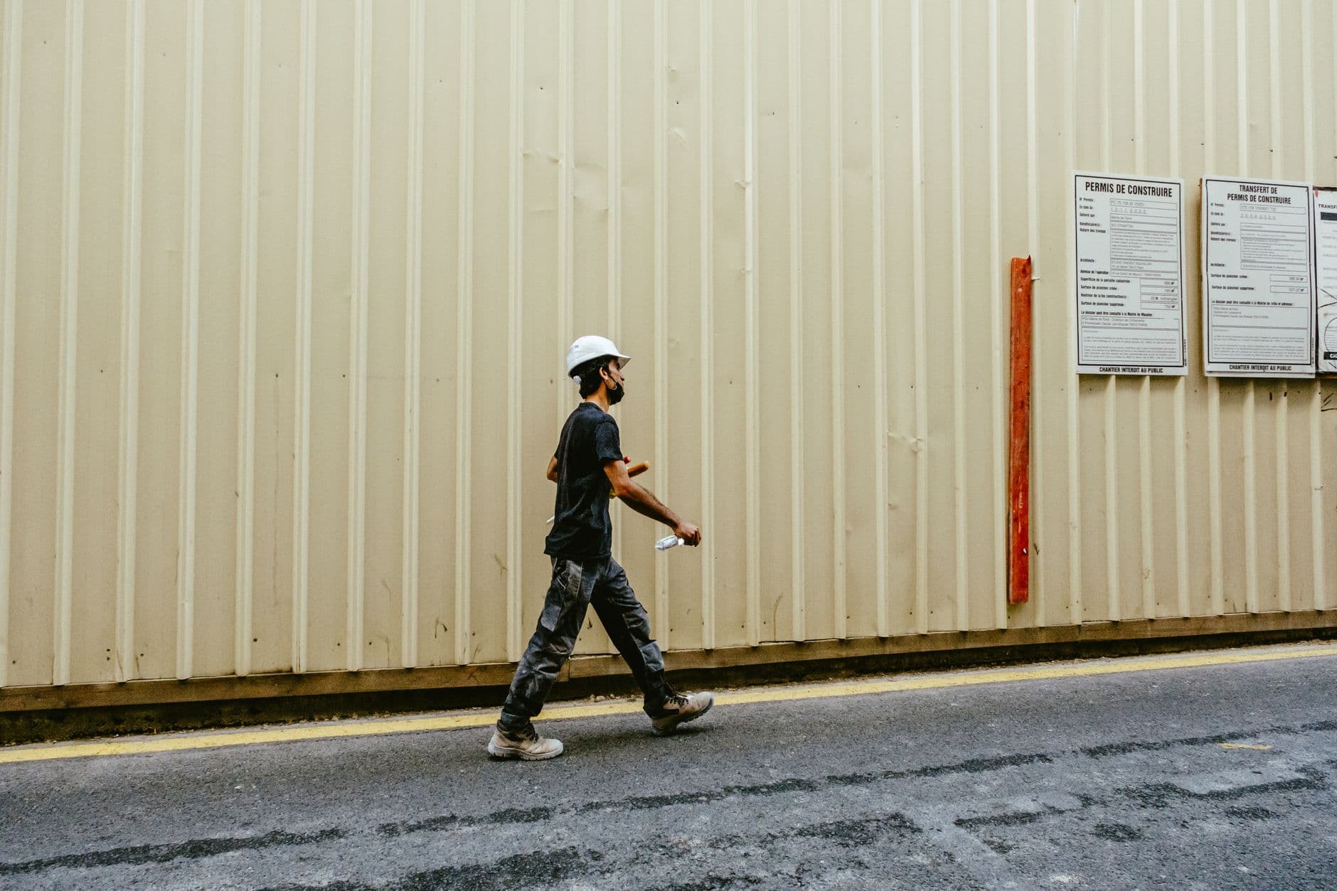 Construction worker wearing full PPE including hard hat, hi-vis vest, and safety boots on a building site