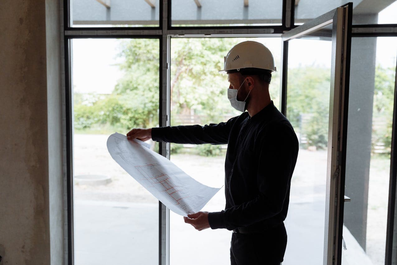 Engineer reviewing risk assessment documents with a floor plan on a construction site