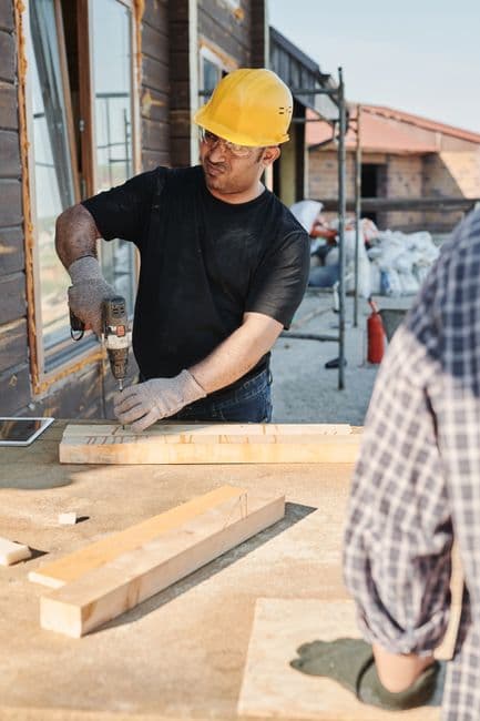 A young worker in high-vis and a hard hat being shown a task by a supervisor on a construction site